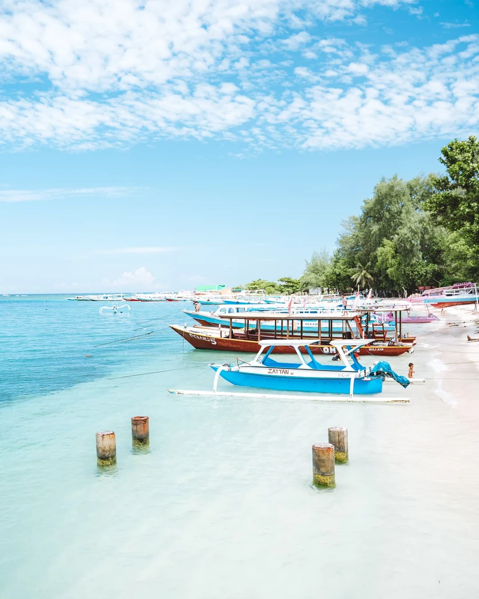 Traditional boats moored on the white-sand beach of Gili Air, with clear turquoise water
