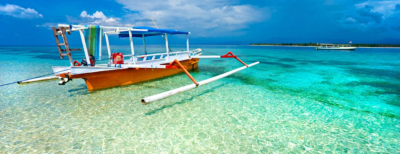 A traditional outrigger boat on clear turquoise water off Gili Air